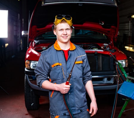 Un apprenti mécanicien en maintenance d'automobiles CFC tient un appareil de soudage