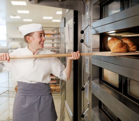 Frau nimmt Brot aus Ofen