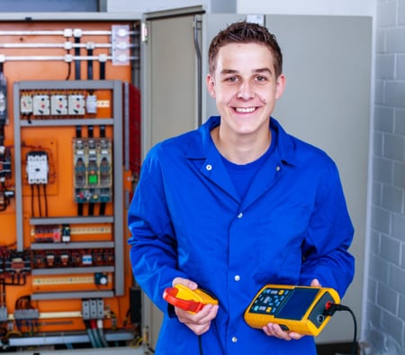 Un apprenti installateur-électricien tient des instruments de mesure dans sa main