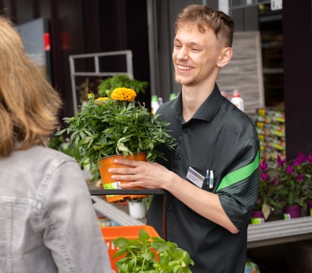 Verkäufer übergibt Kundin Blumen