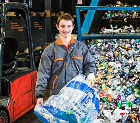 Un apprenti recycleur tient un sac plastique pour bouteilles en PET