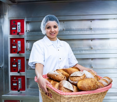 Une apprentie boulangère-pâtissière-confiseuse tient un panier avec du pain
