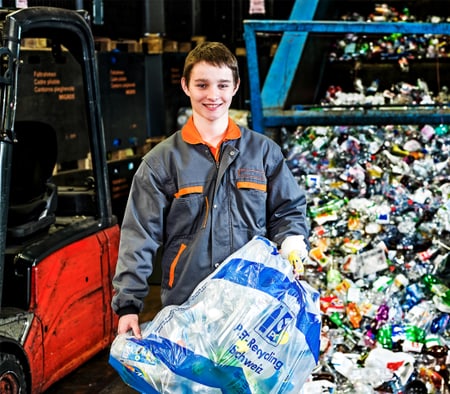 Lernender Recyclist hält einen Plasticksack für Petflaschen