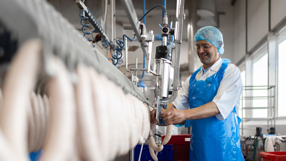 Fröhlicher Mitarbeiter bei der Wurstproduktion