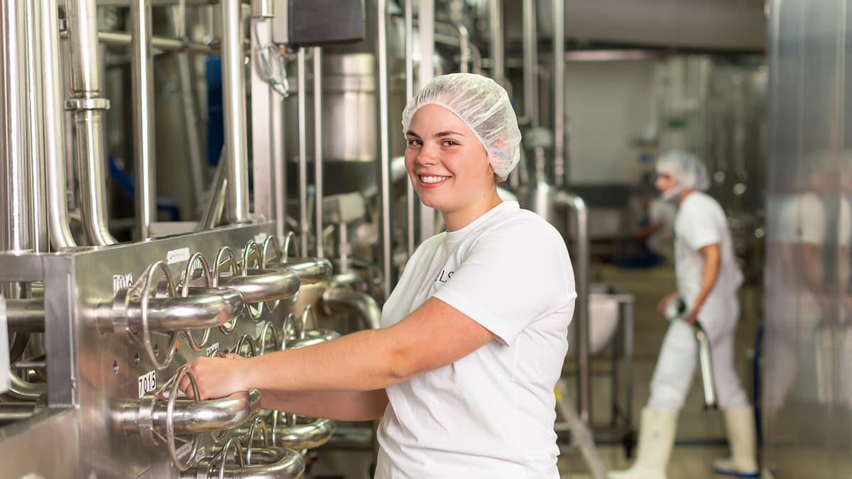 Lernender Michlchtechnologe hält Glas voll Milch in der Hand