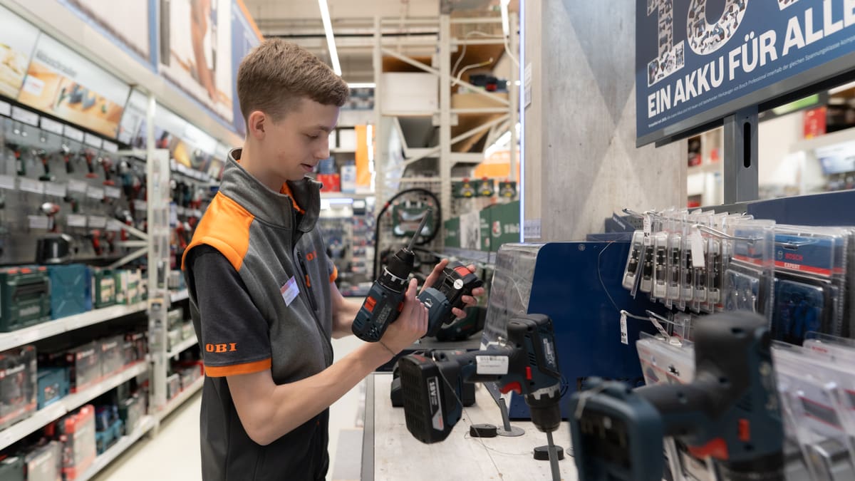 Junger Mann hält Bohrmaschine in den Händen