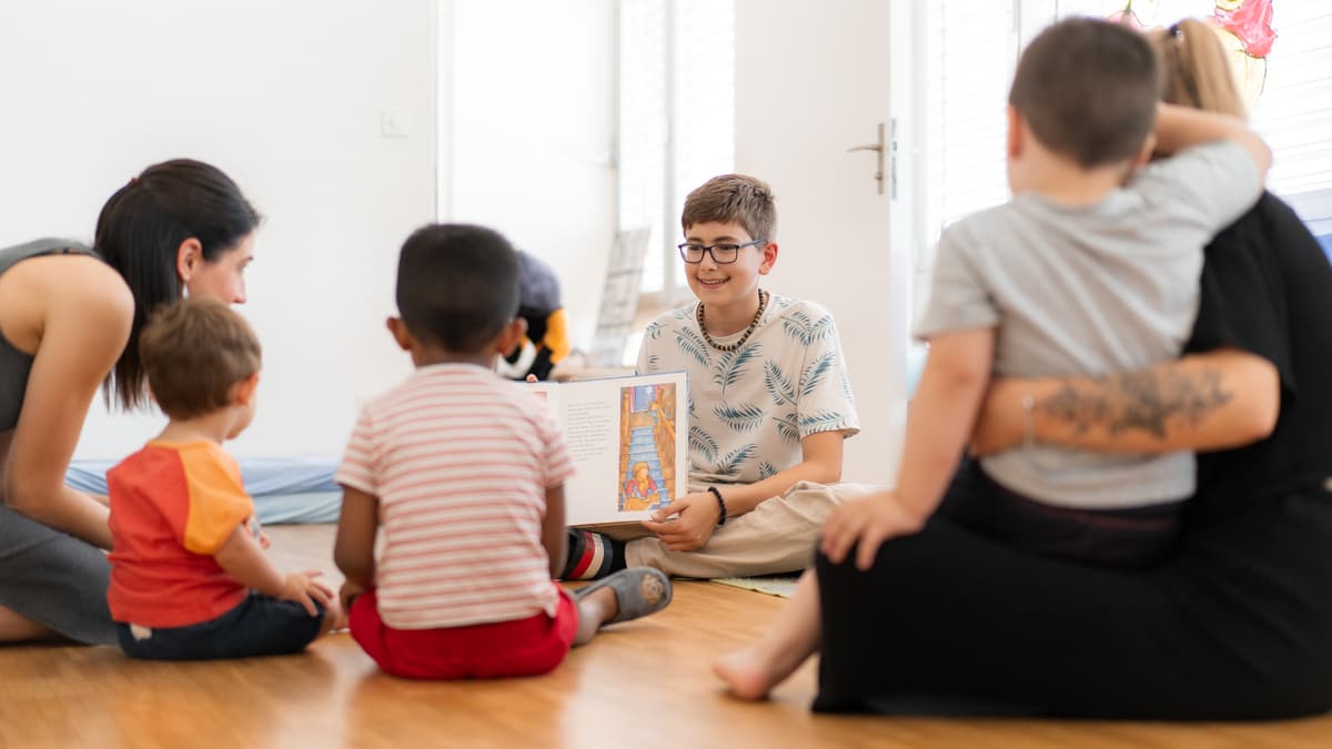 Kinder sitzen gemeinsam im Kreis und schauen sich Bilderbuch an