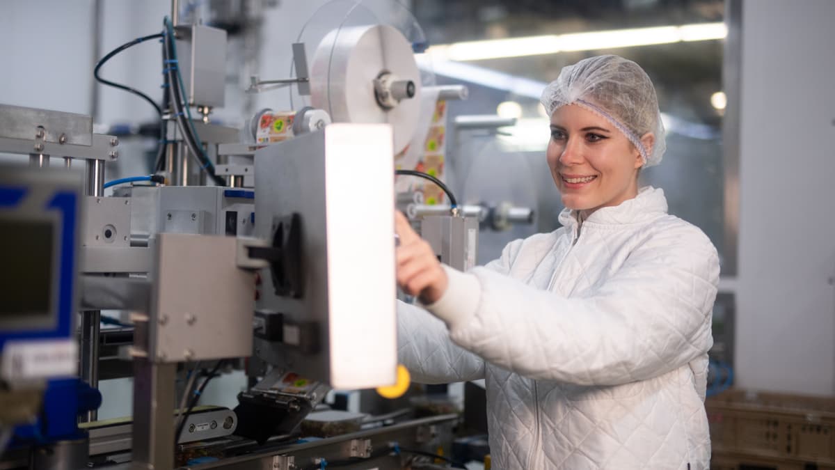 Frau hantiert an Produktionsanlage für Mozarella Frau hantiert an Produktionsanlage für Mozarella
