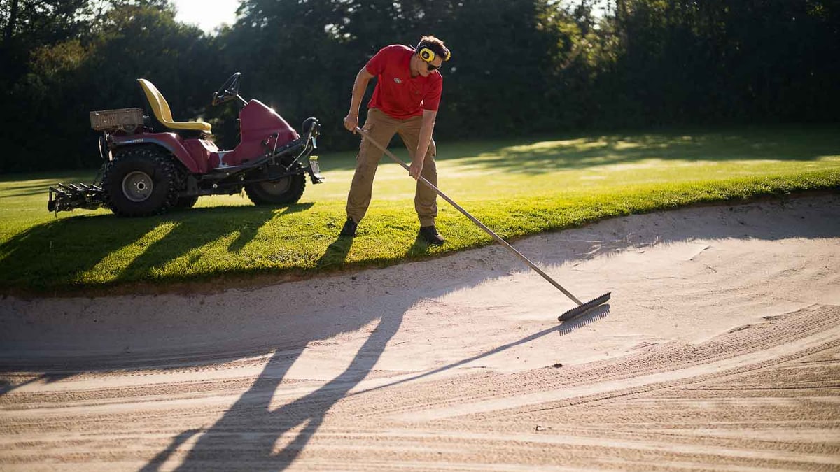 Mann pflegt den Golfplatz