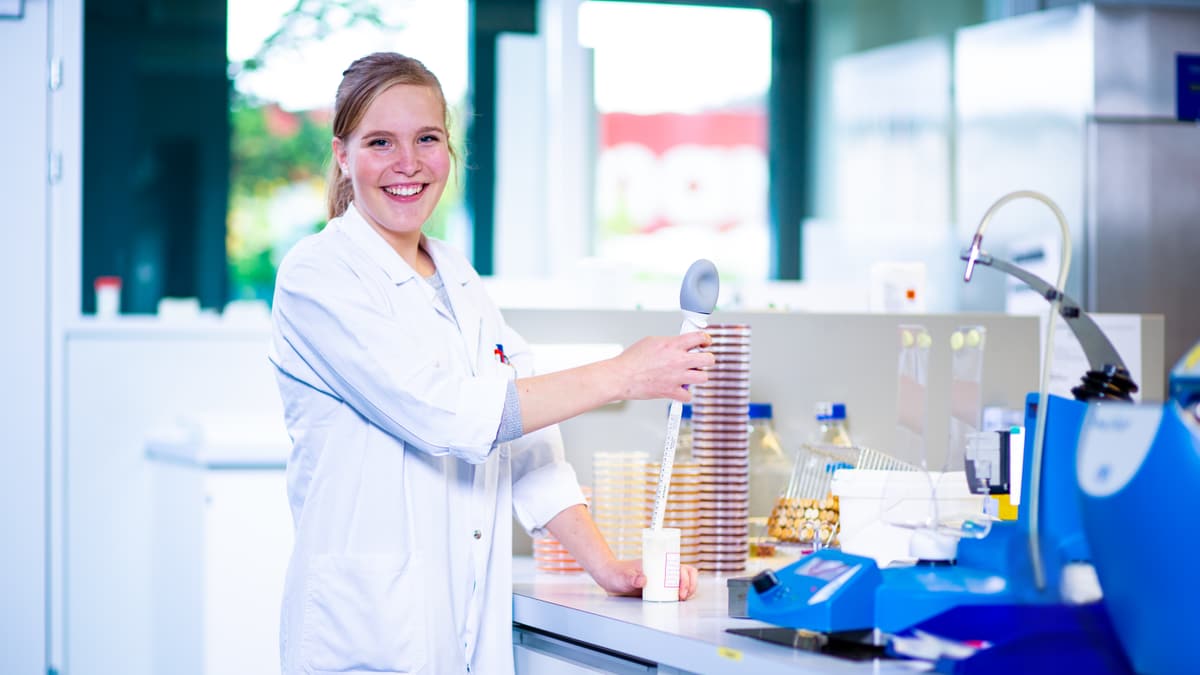 Lernende Laborantin Biologie hält Messgerät an ein Becher