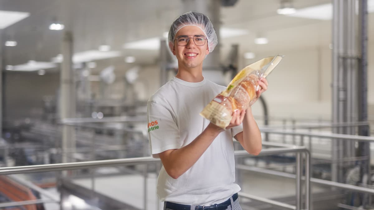 Mann hält Brot in Händen und lächelt in Kamera