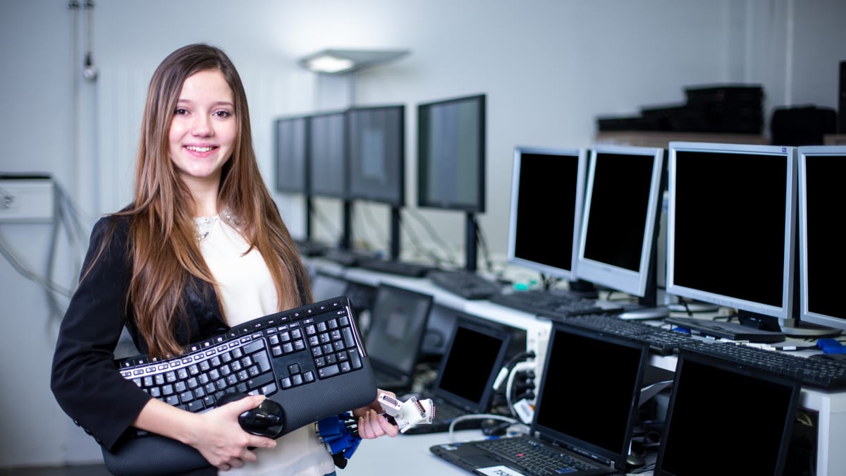 Une apprentie informaticienne orientation informatique d’entreprise se tient devant des écrans