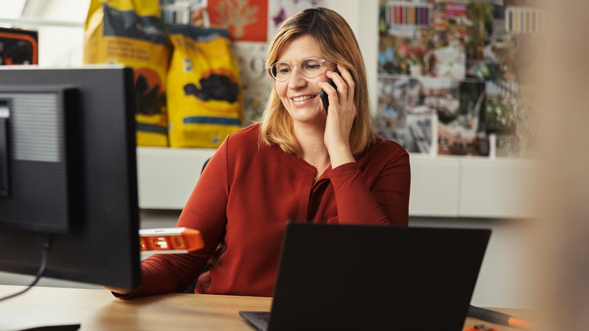 Frau am Telefon mit Wasserwage in der Hand