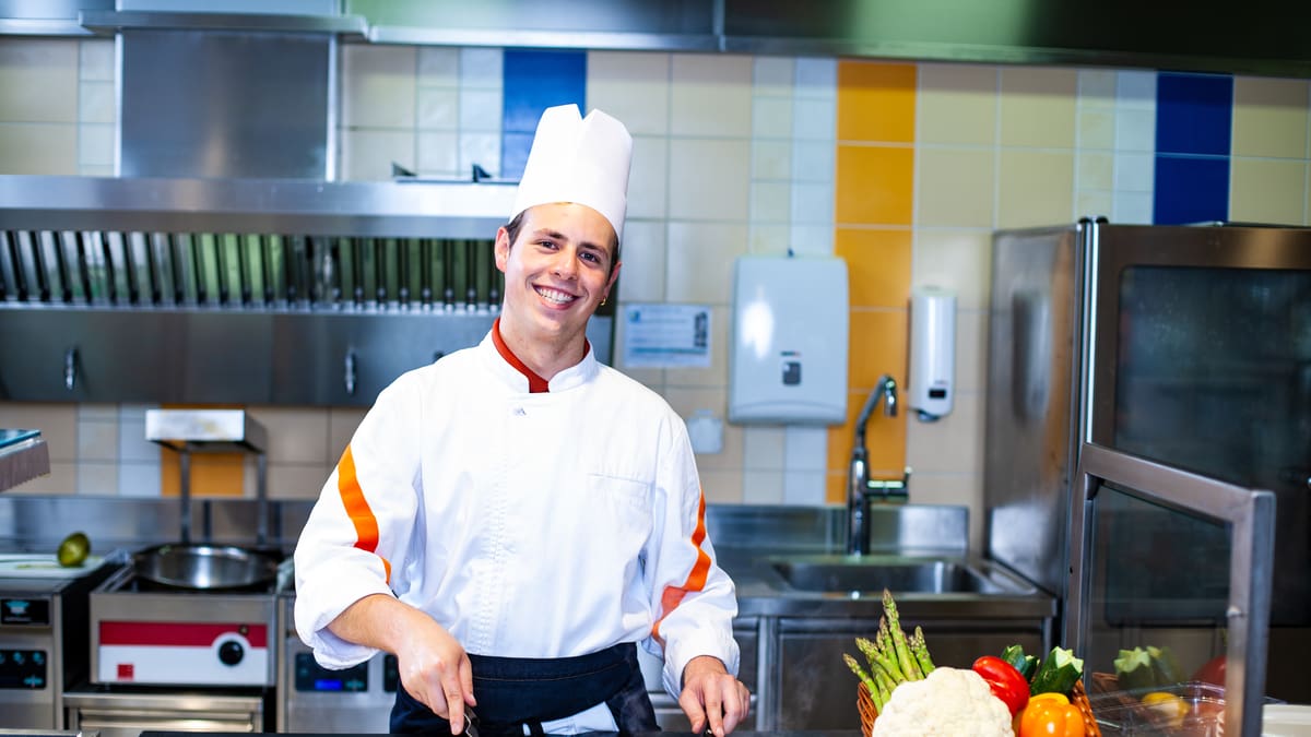 Un apprenti employé de cuisine fait dorer des légumes