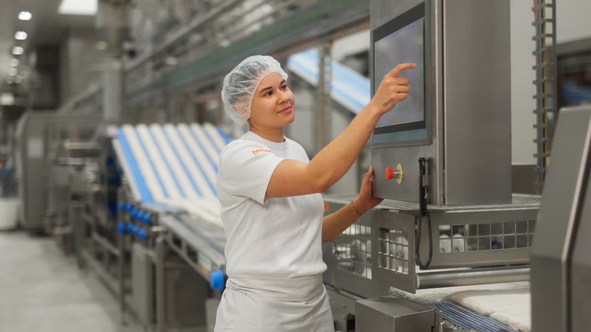 Anlagenführerin drückt auf Touchscreen einer Produktionsanlage