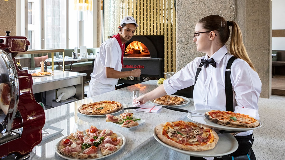 Servicemitarbeiterin serviert Pizze