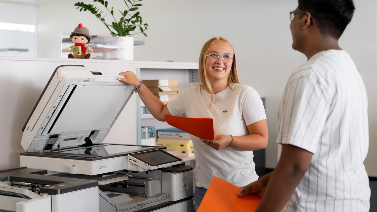 Frau und Mann verwenden Drucker und lachen