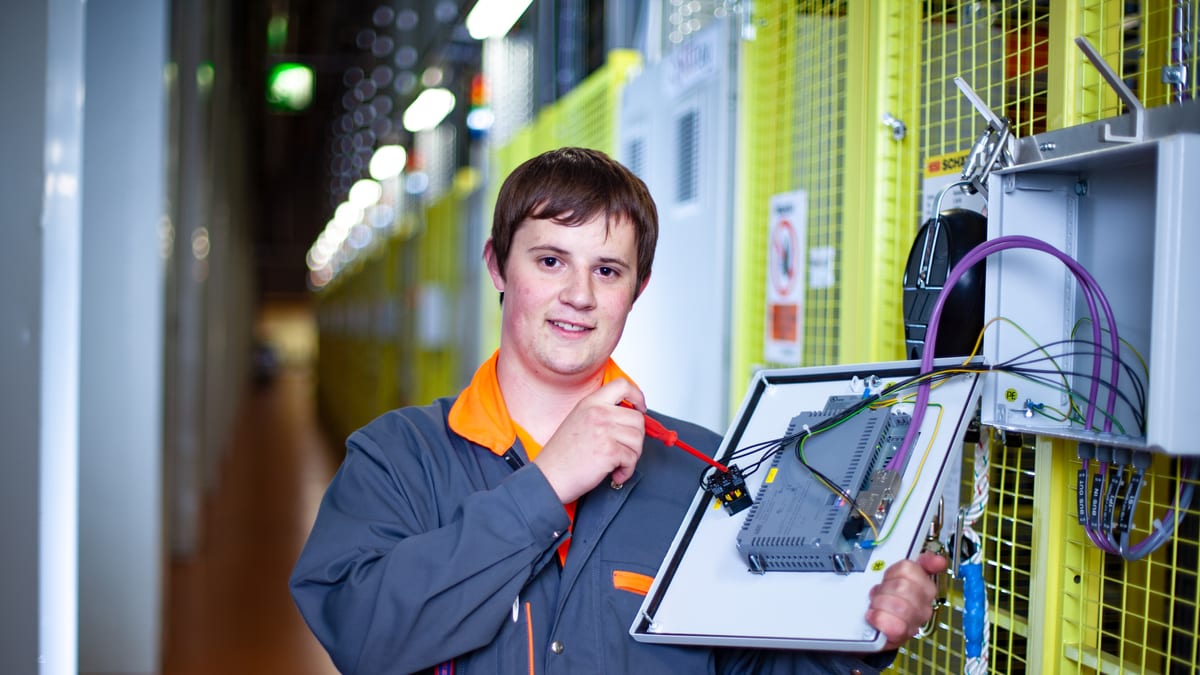 Un apprenti monteur automaticien visse une machine