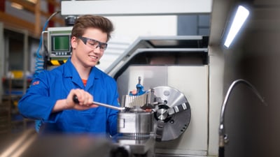 Polymechaniker dreht etwas an an Produktionsanlage