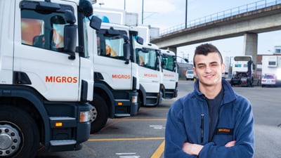 Un apprenti conducteur de véhicules lourds se tient devant des poids lourds stationnés