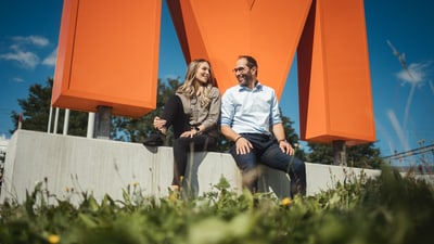 Zwei Mitarbeitende vor dem grossen Migros Zeichen