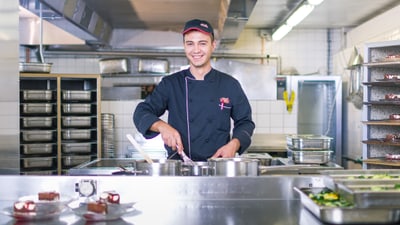 Junger Koch rührt in Pfanne