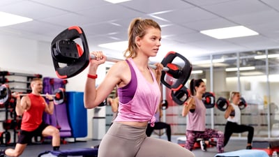 Frau mit Langhantel im Group Fitness