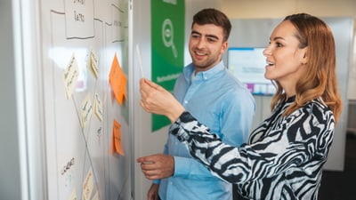Zwei Personen an Whiteboard mit Post-Its
