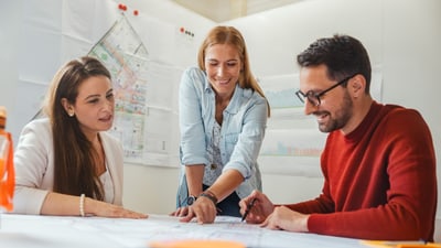 Drei Personen besprechen Pläne im Sitzungszimmer