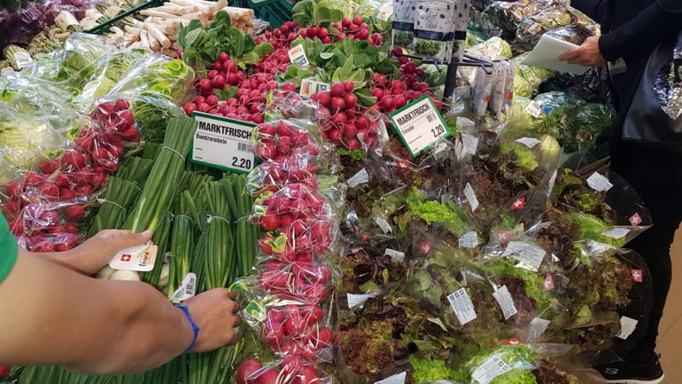 Person sortiert Salate im Supermarkt