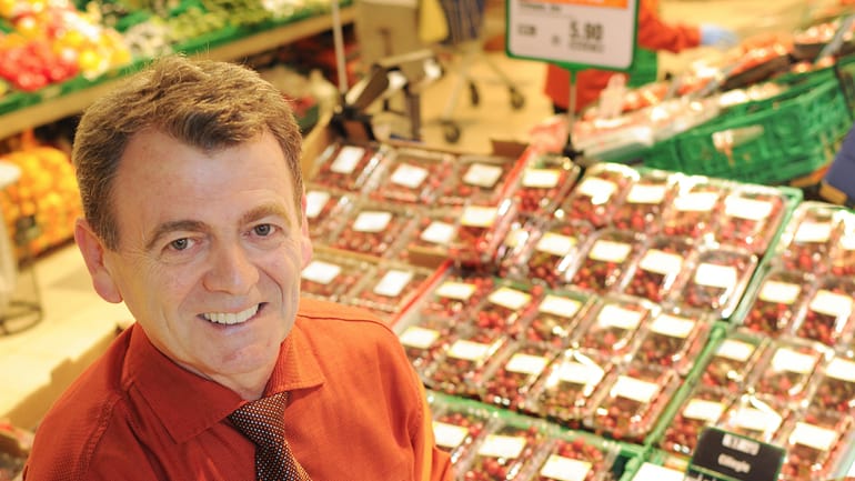 Collaborateur présentant des cerises au rayon Fruits