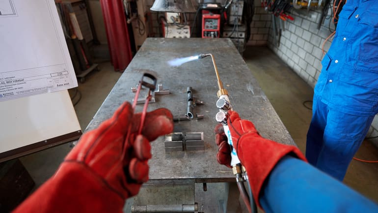 Hand mit roten Handschuhen am schweissen 