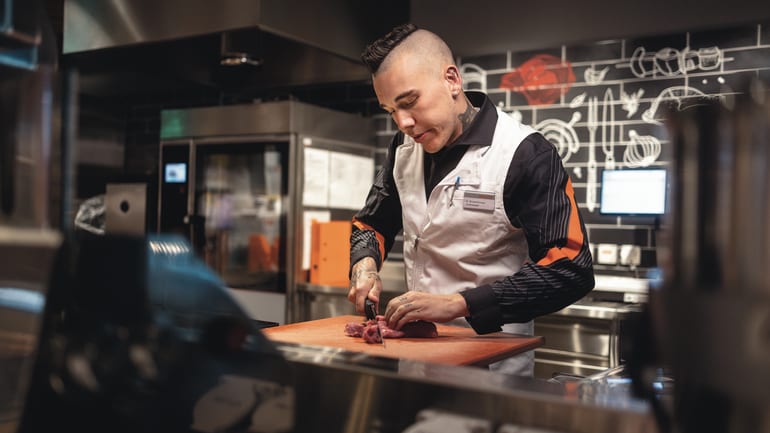 Metzger schneidet Fleisch in einer Migros Filiale
