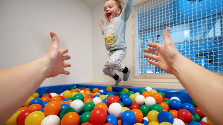 Un bambino salta in una piscina di palline colorate