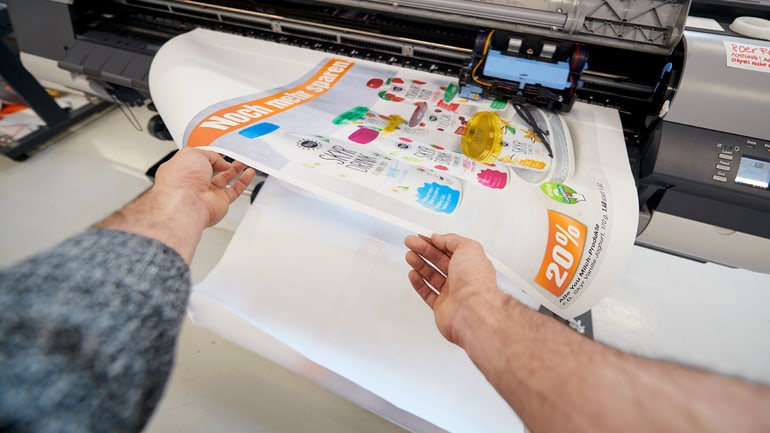 Mani tengono un poster fresco di stampa