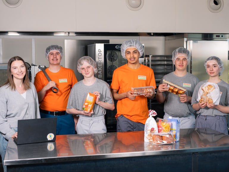 6 Jugendliche stehen beisammen und halten diverse Migros Produkte in den Händen