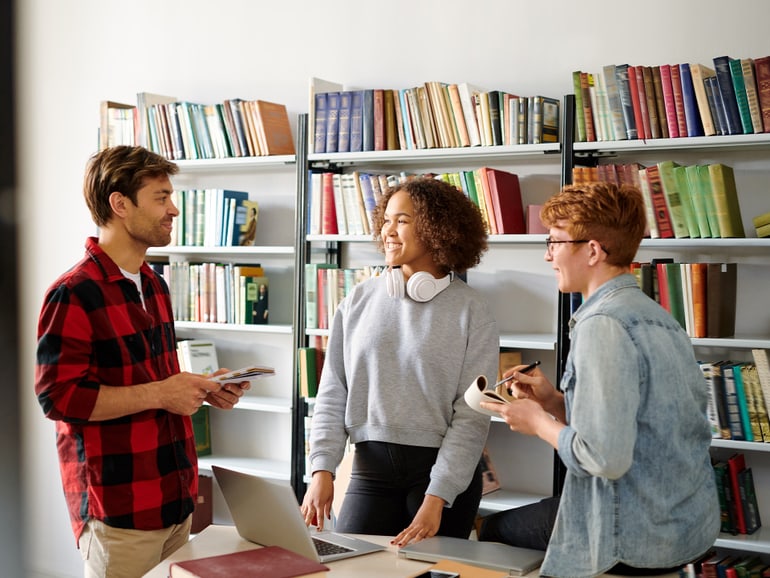 Drei Erwachsene in einem Gespräch in der Bibliothek