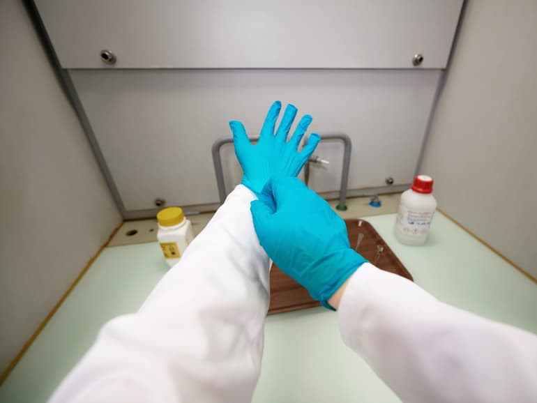 Hände mit blauen Gummihandschuhen