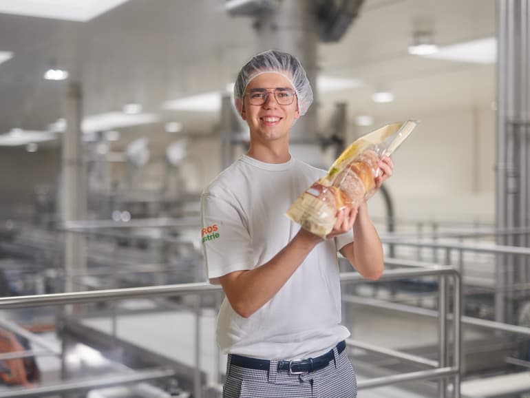 Mann hält Brot in Händen und lächelt in Kamera