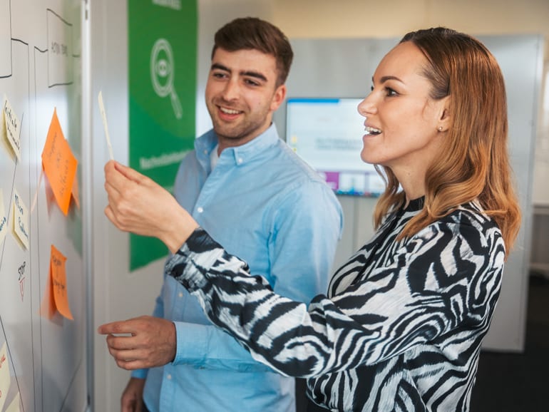 Zwei Personen an Whiteboard mit Post-Its
