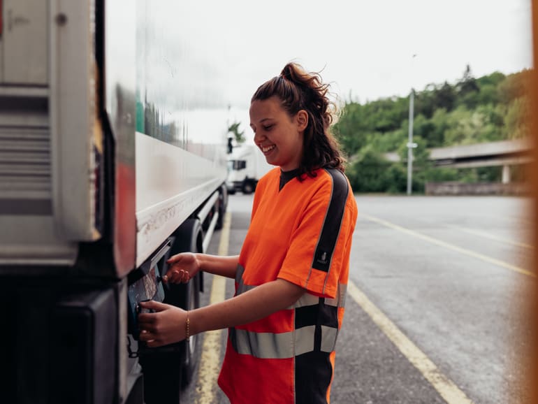 Junge Frau stellt etwas an LKW ein