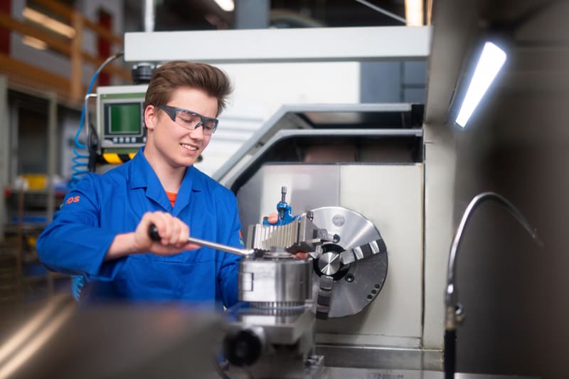 Polymechaniker dreht etwas an an Produktionsanlage