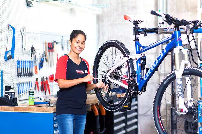Un'apprendista meccanica di biciclette lavora con un cacciavite su una bicicletta