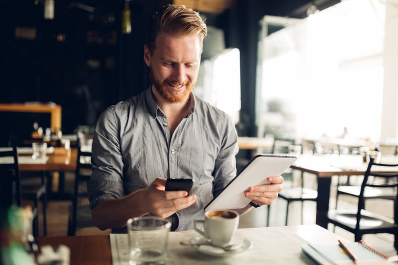 Mann mit Handy und Tablet in der Hand
