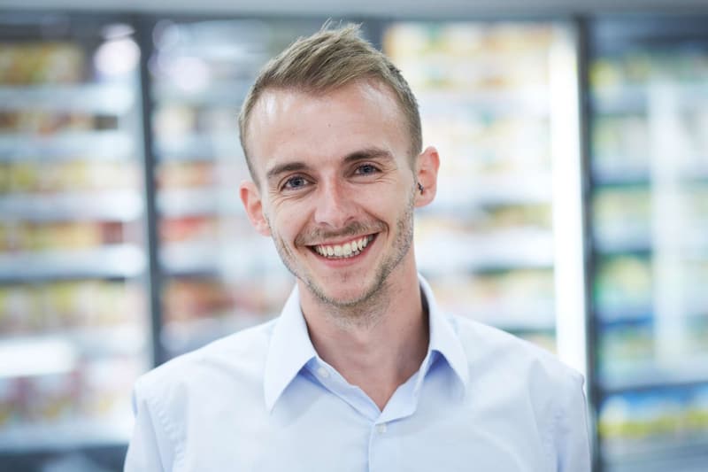 Giovane uomo sorridente con camicia bianca