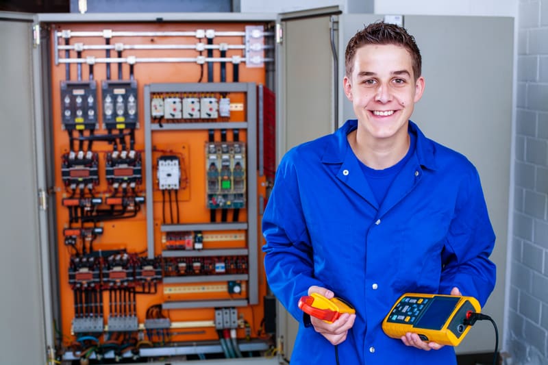 Un apprendista installatore elettricista tiene in mano degli strumenti di misurazione