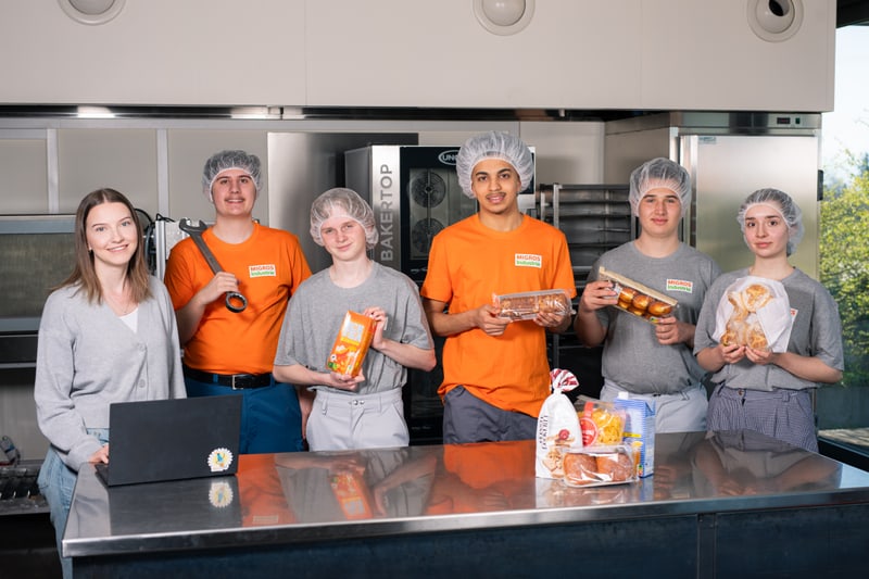 6 Jugendliche stehen beisammen und halten diverse Migros Produkte in den Händen