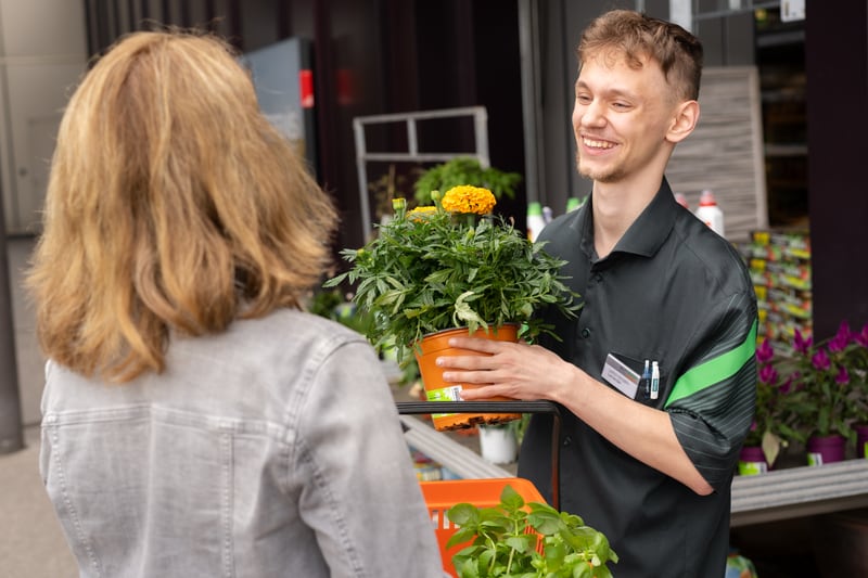 Verkäufer übergibt Kundin Blumen