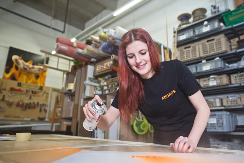 Un'apprendista decoratrice 3D spruzza la vernice su uno stencil