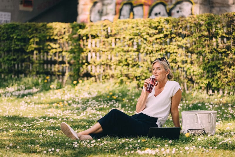 Frau auf einer Wiese am Trinken